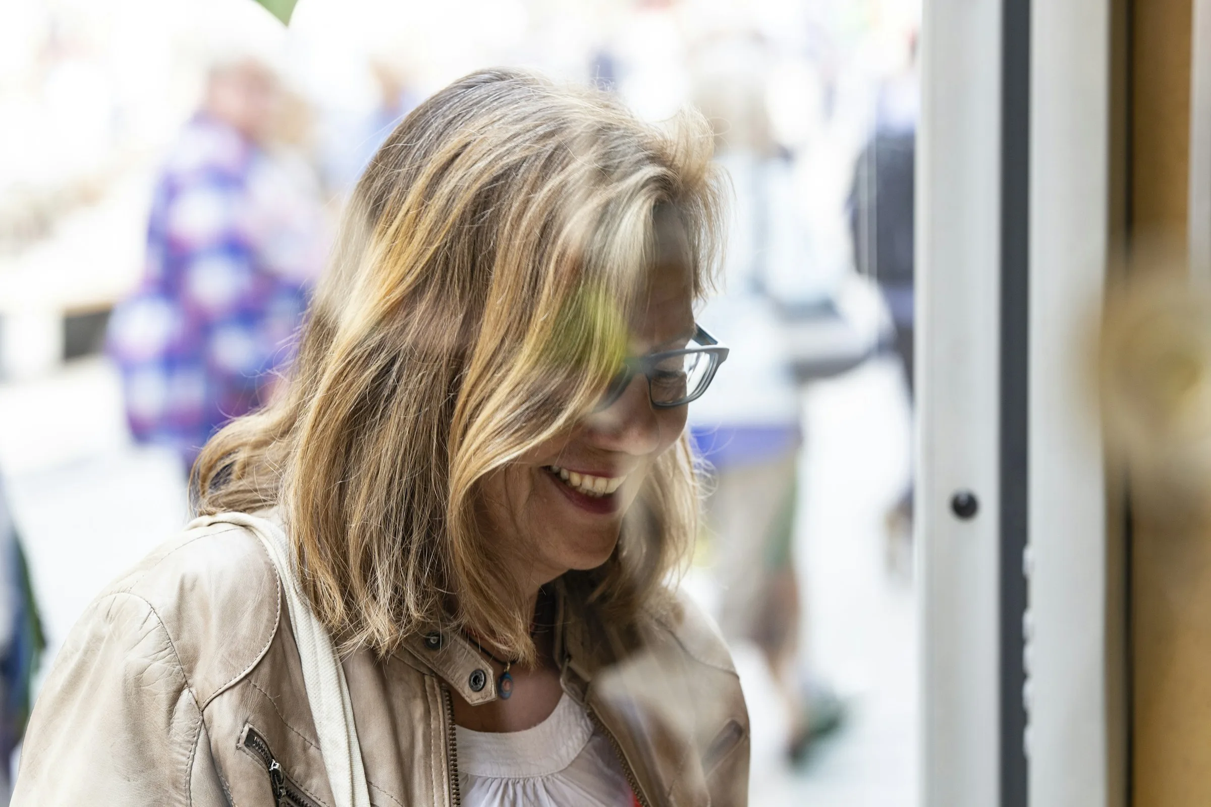 A mature woman in glasses sharing a warm, candid smile
