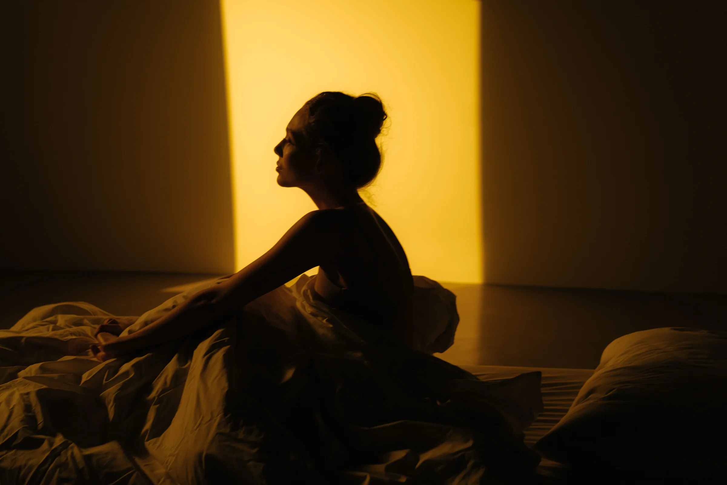A woman sitting quietly in bed in warm morning light